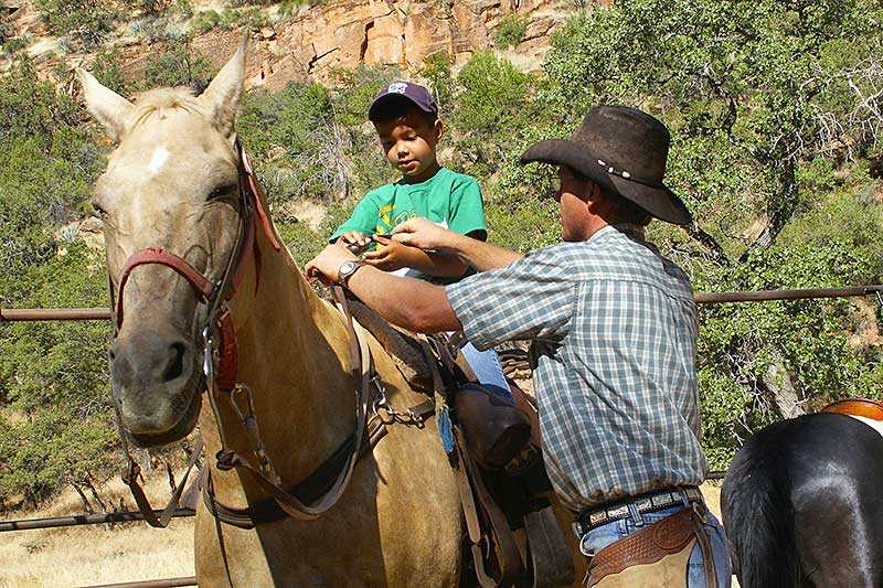 zion-national-park-a-wrangler-helps-a-park-guest-saddle-up-for-the-horseback-ride