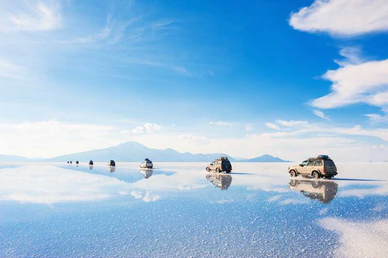 Salar De Uyuni, Bolivia - March, 26, 2017 Off-Road Cars Driving Through The Salt Flat Salar De By Desizned