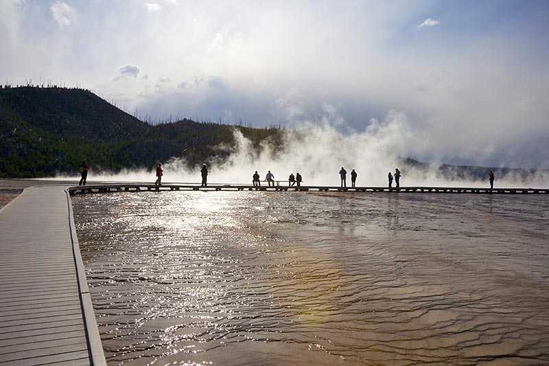 yellowstone-national-park-tourists-standing-against-a-steamy-backdrop-in-front-of-mineral-terraces