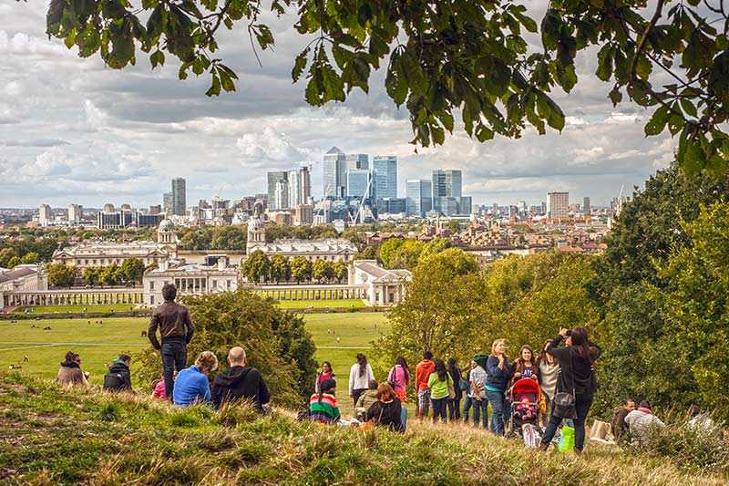 greenwich-park-visitors-enjoy-the-view-of-the-canary-wharf-skyscrapers-from-greenwich-park-in-london